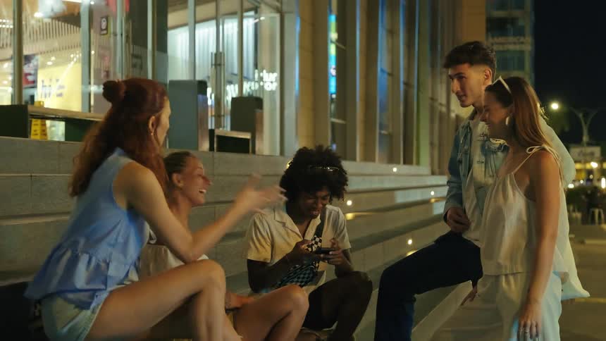 Group of young people sitting on outdoor steps at night