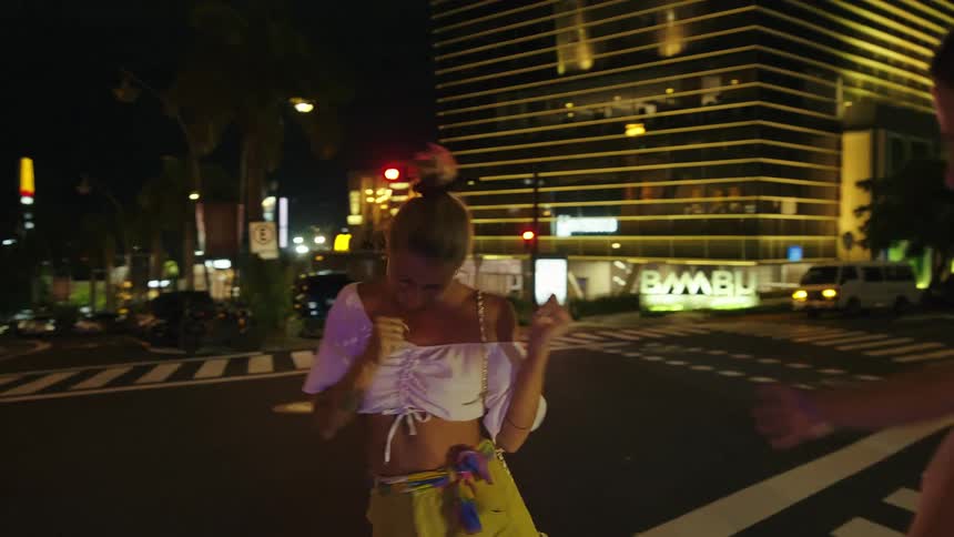 Two young woman stop to playfully dance as they walk in a crosswalk
