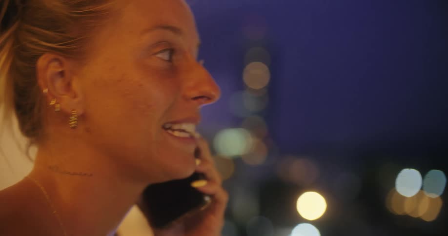 The woman is smiling while talking on her phone