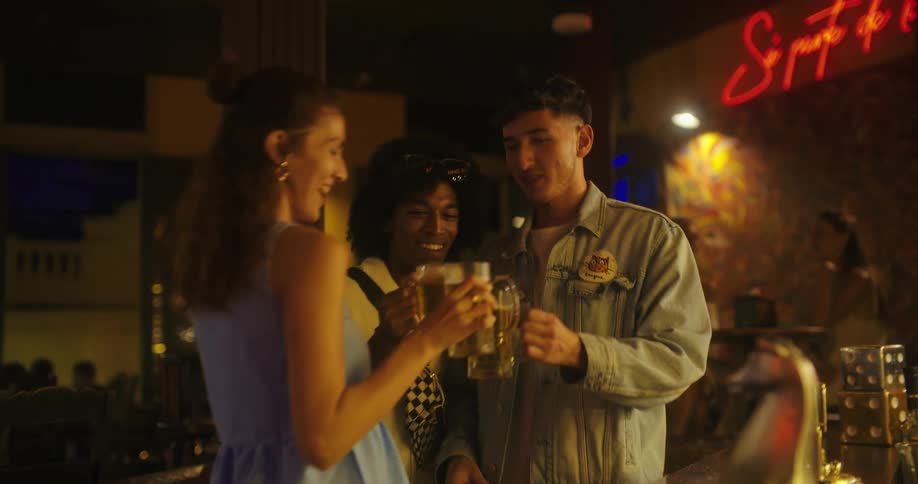 A group of friends pick up drinks at the bar and then go to their table in a night club