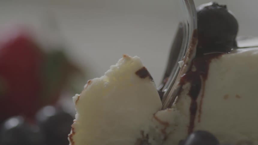 A person using a fork to cut a piece from a cake with white chocolate on top
