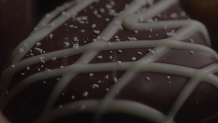 A rich chocolate treat is striped with white icing and sprinkled with salt