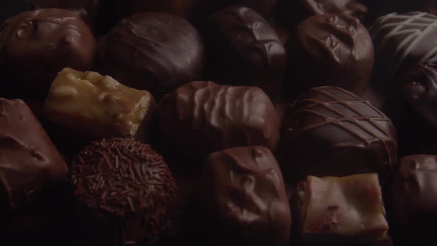 A variety of different chocolates some with sprinkles and some with caramel or nuts are arranged together in a closeup shot