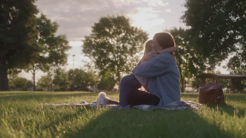 A girl hugs her mother at a picnic