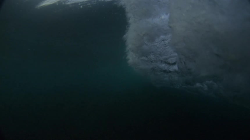 Wave breaking near a cliff under a partly cloudy sky