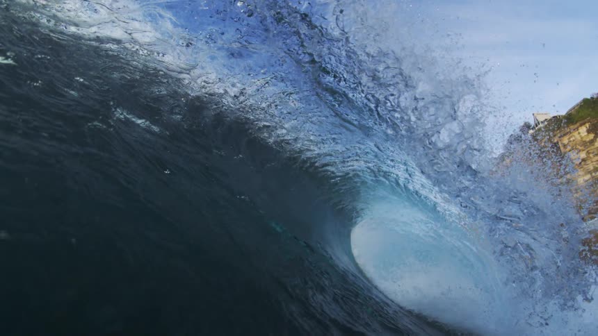 Huge wave curls and splashes as it rolls into shore and the view goes underwater