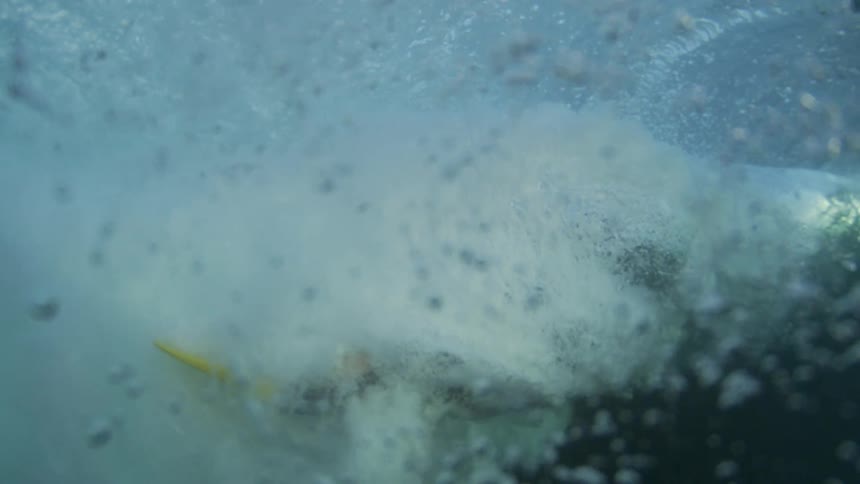 A strong ocean wave breaking and exerting force underwater quickly pushing bubbles forward