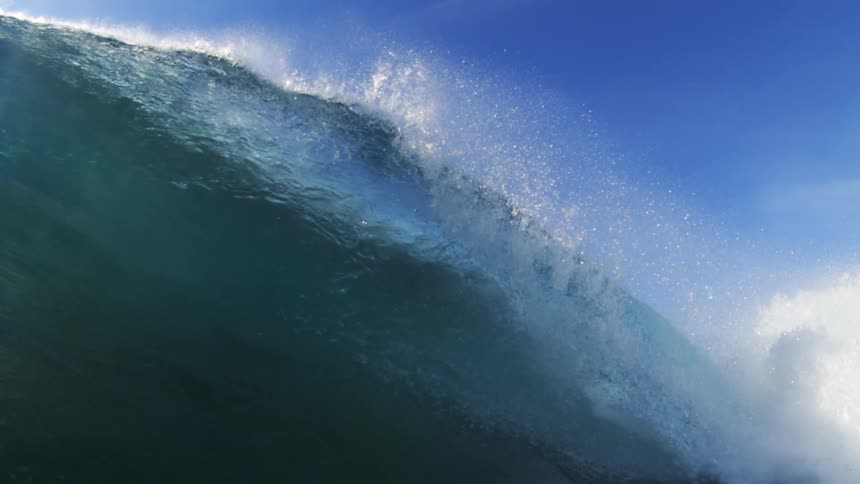 A large powerful wave cresting and beginning to crash capturing both the intense white foam and the blue of the water from an inwater perspective