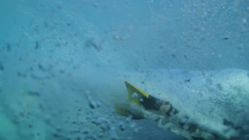The man dives under the wave swimming underwater