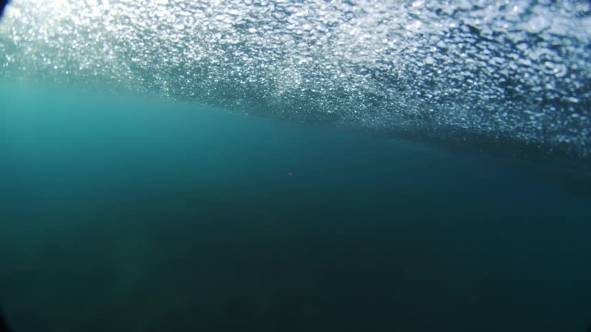 The video shows a unique perspective of a wave crashing with the camera split between the view above and below the waters surface the top half of the screen shows the foamy frothy surface of the water while the bottom half is a deep blue and calm
