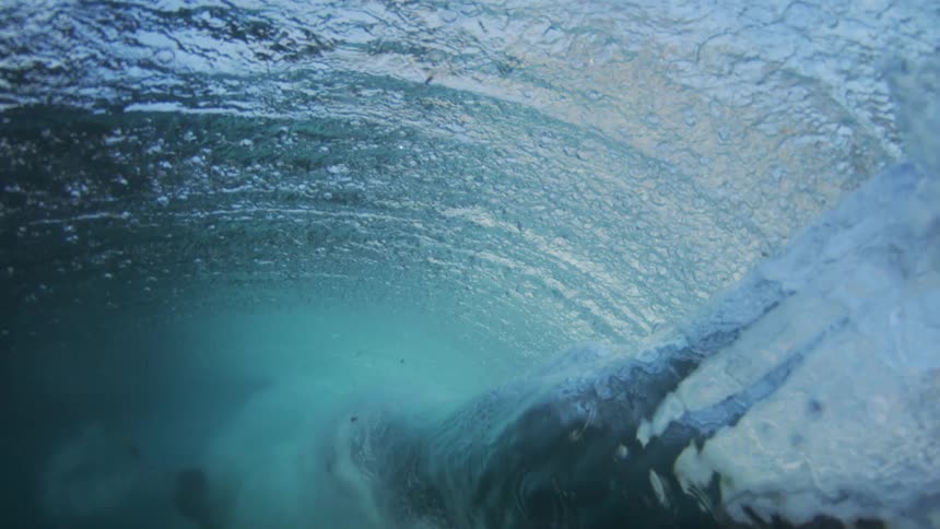 Huge wave curls and splashes as it rolls into shore and the view goes underwater