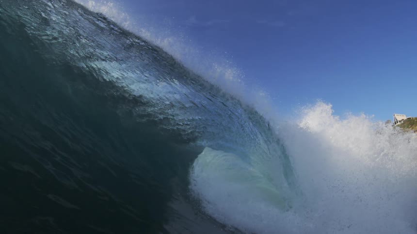 A large ocean wave breaking on its surface creating a large tube and causing movement underwater
