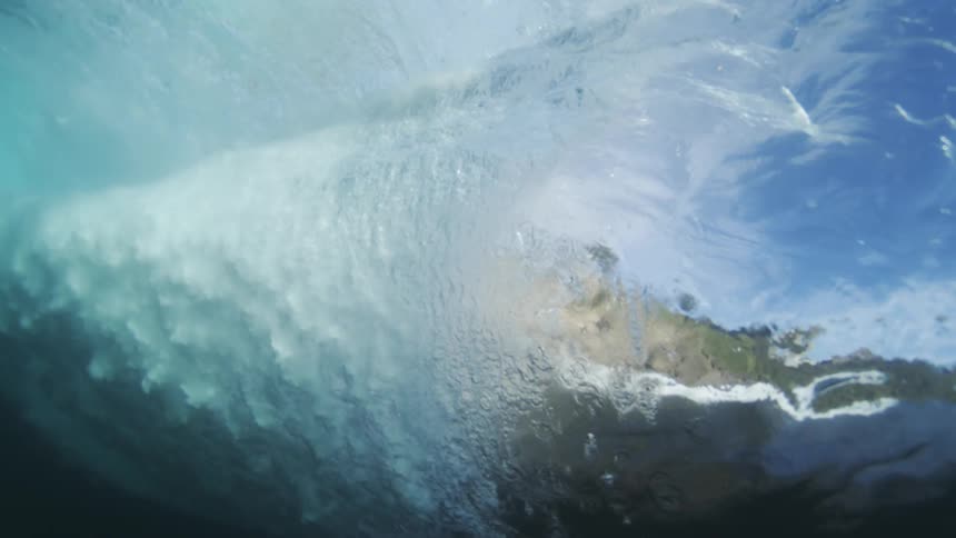 The wave rolls underwater by the shore