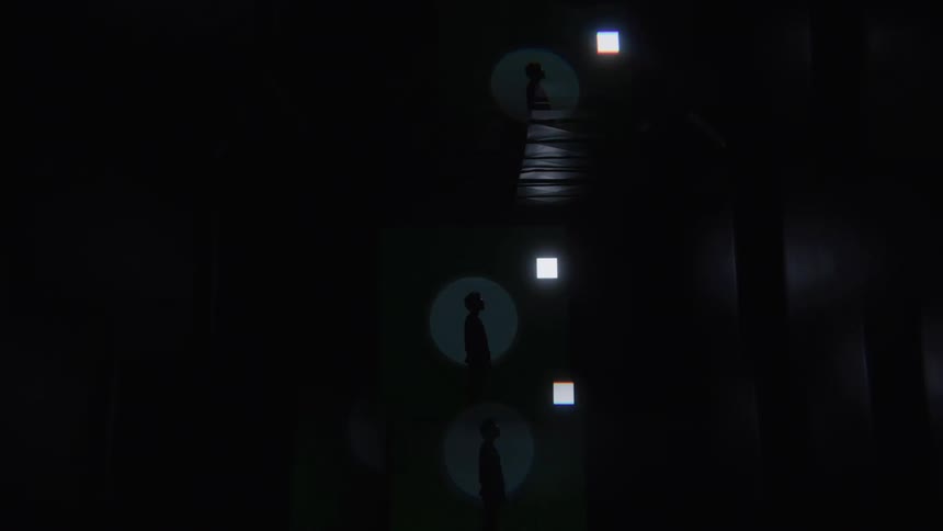 A view of a stage shows a person standing in the center of a large circular beam of light while three other similar lights around