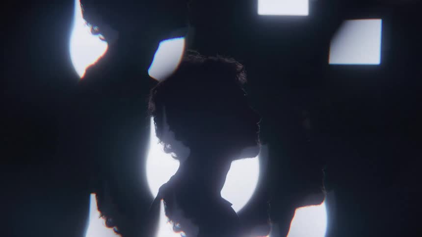 A persons head and shoulders are shown in a silhouette against a bright abstract background of white light with their side profile clearly visible