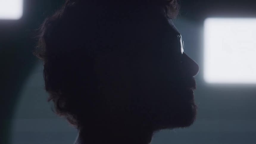 The video shows a man in a silhouette against a bright white background he is wearing glasses and looking to the right the words filmsupply are visible as a watermark on the video