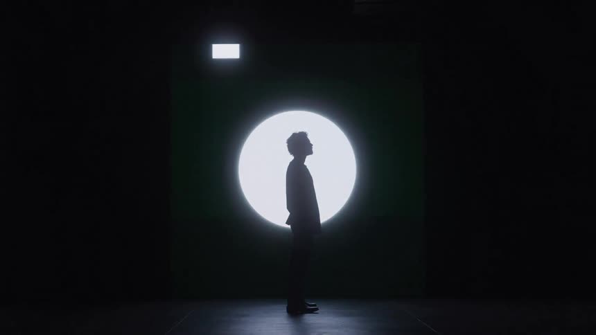 Silhouette of person standing in front of illuminated geometric shapes
