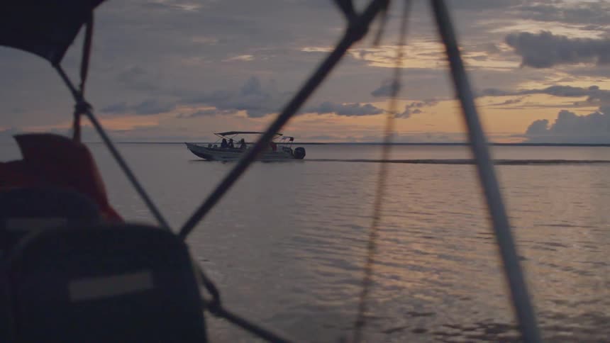 Boats sail and dock near the shore during sunset