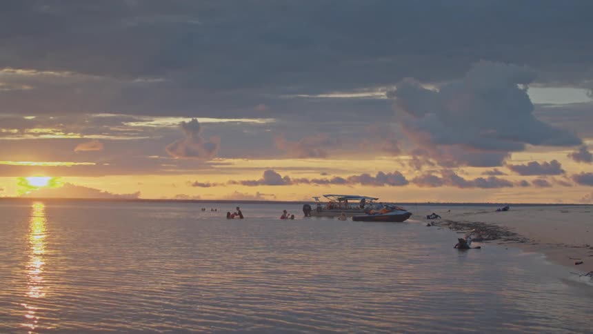 People are swimming around the boat anchored near the sand