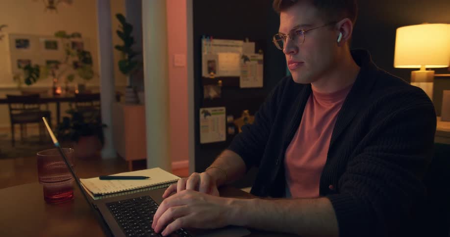 A young man works on his laptop in a cozy living room