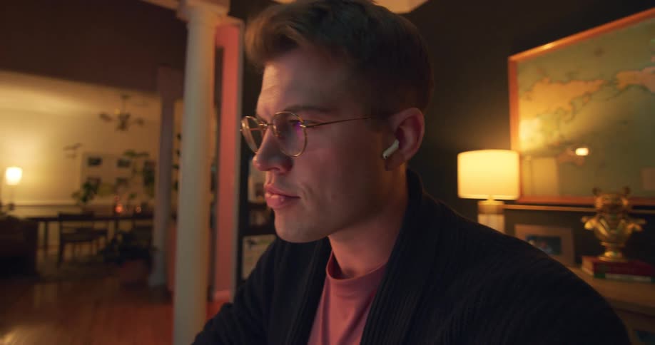 A person is focused on a screen in a dimly lit living room indoors