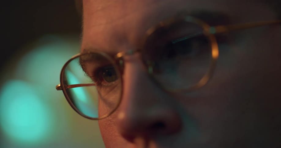 Extreme close up of a young mans face as he uses a laptop computer in a room