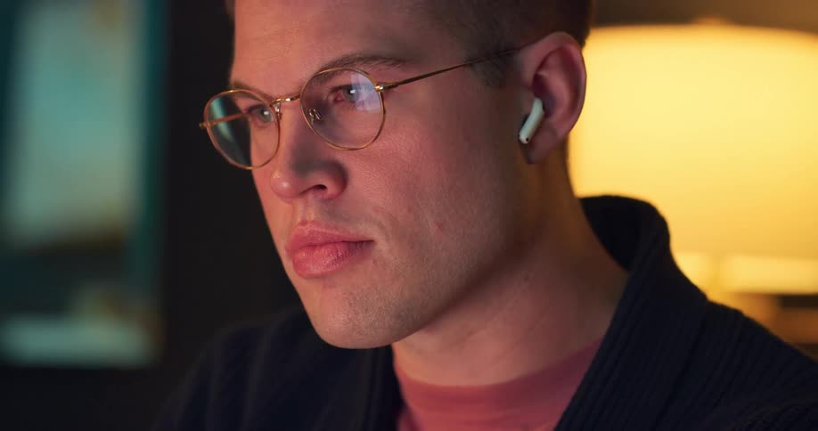 Man concentrates on a screen with earbuds in