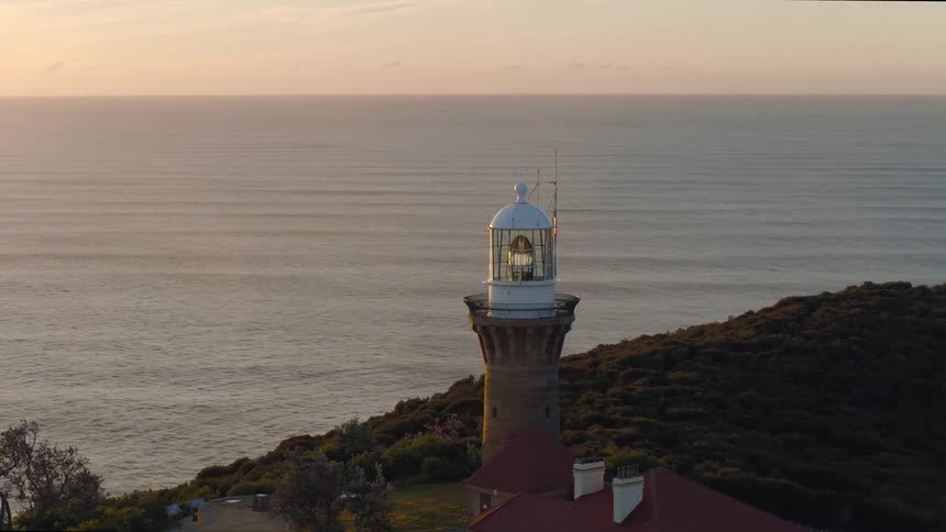 Aerial of a coastal lighthouse at sunset