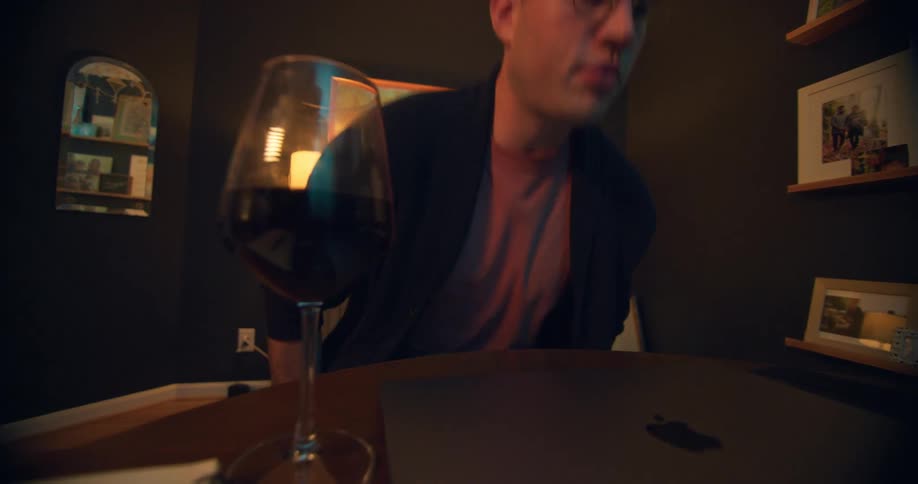 Man sitting in an office drinks red wine from a glass