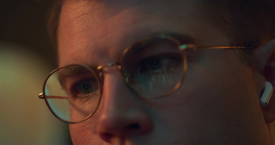 Man wearing eyeglasses focuses on a computer screen