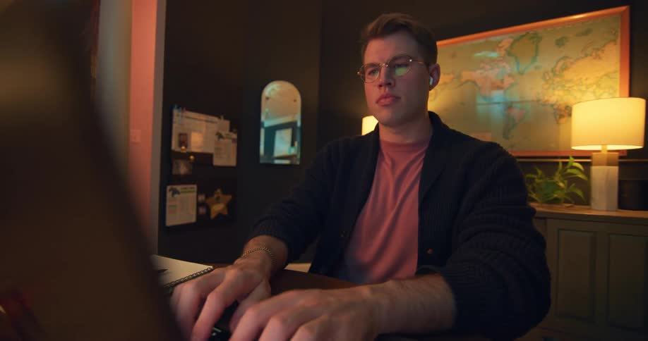 A man working on a laptop in a warmly lit home office