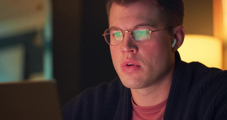 A man takes a drink while sitting in front of his laptop computer