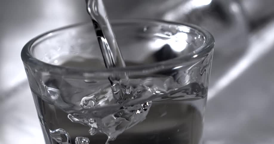 Close up of a transparent liquid poured into a small glass cup