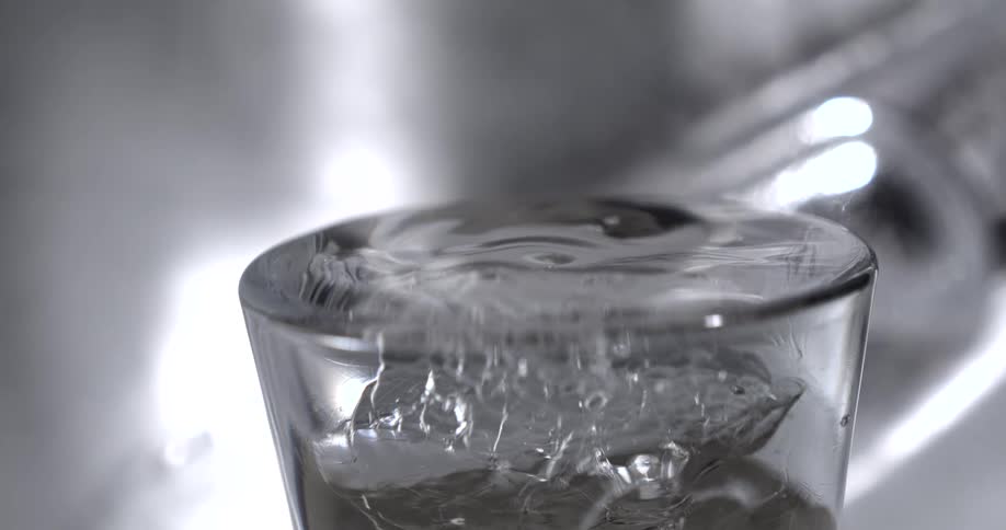 The video shows a closeup shot of a clear glass being filled with water from a faucet the water is shown splashing and overflowing from the top of the glass the words filmsupply are visible as a watermark on the video