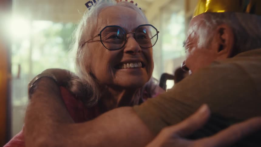 An elderly couple warmly embraces during a joyful birthday celebration