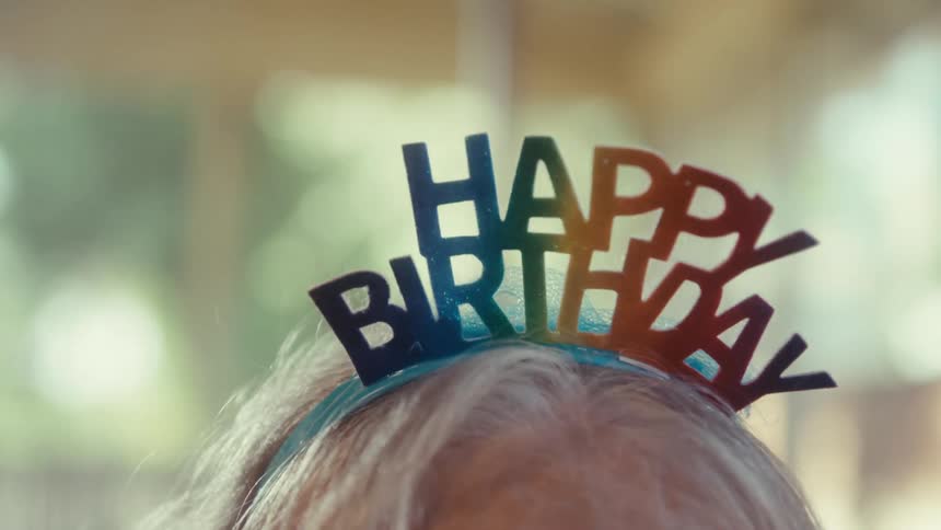 Elderly woman wearing a happy birthday headband