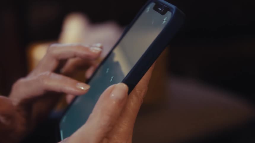 A closeup shot of a persons hands as they actively swipe and use their fingers on a smartphone screen