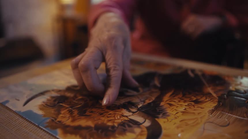 Elderly hand fits a piece into a puzzle with an animal image