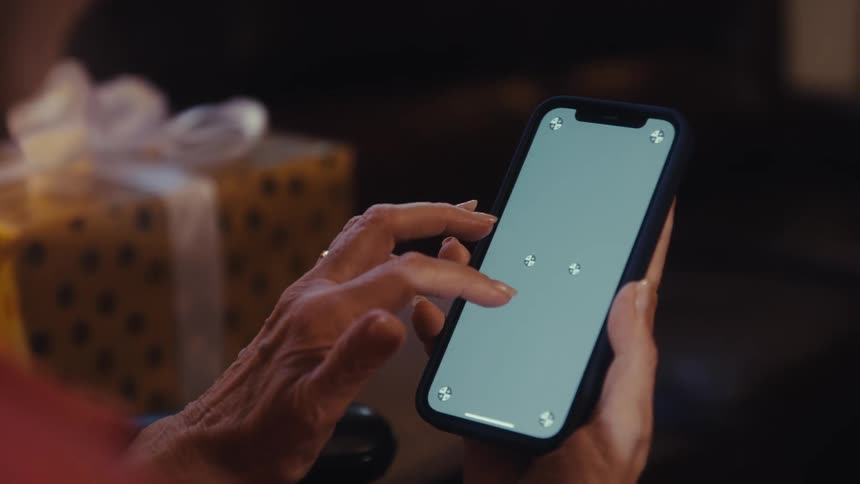 The video shows an extreme closeup of a persons hands as they scroll and pinch to zoom on a cell phone with a green screen on the display the word filmsupply is visible as a watermark on the video