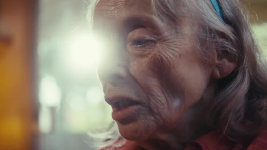 Elderly woman reacts to a video call on her phone at a party