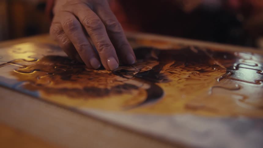 Elderly lady placing the last piece of the puzzle on the table