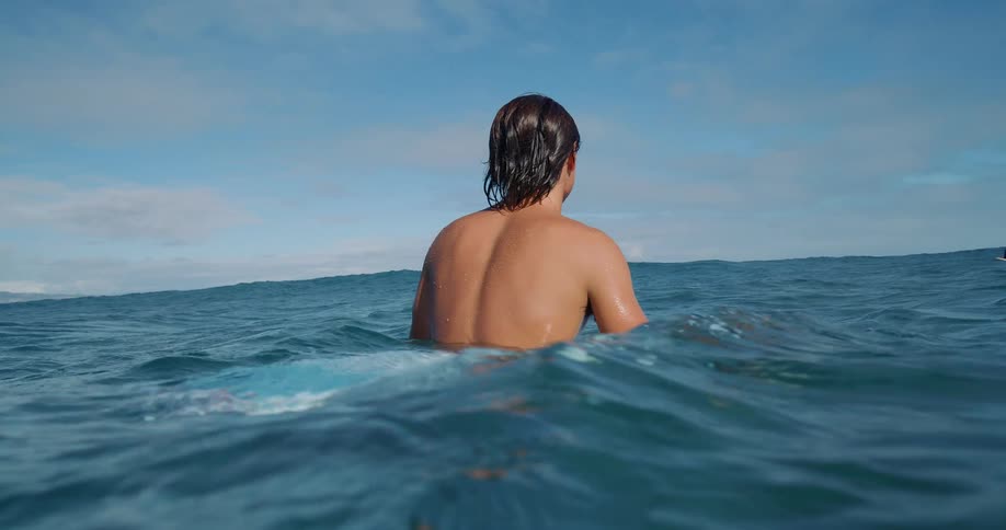 Person facing the horizon while in the sea under a blue sky