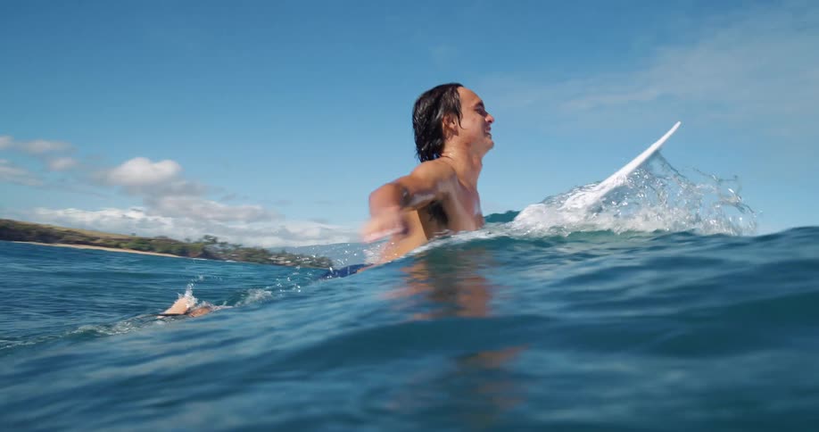 Surfer paddling on his surfboard over small waves