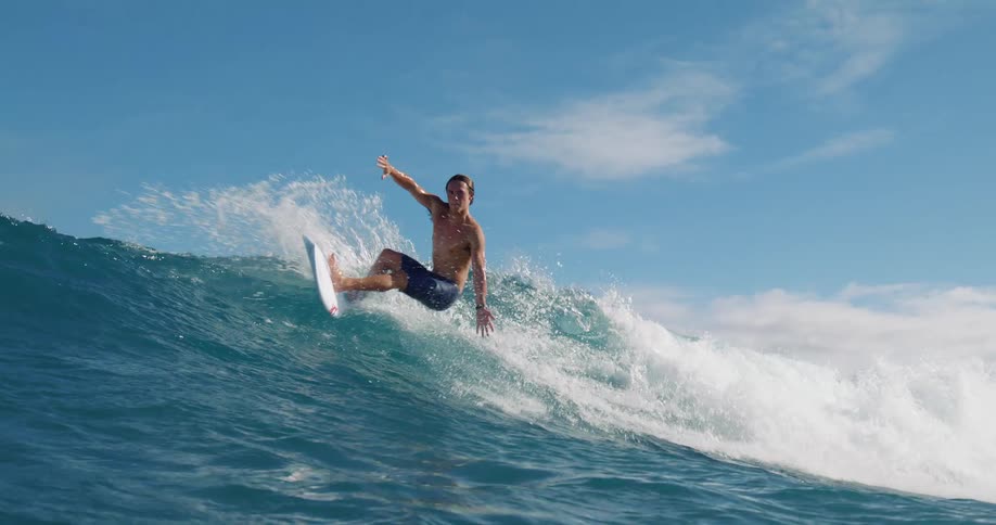 Surfer rides a wave and water splashes as he turns