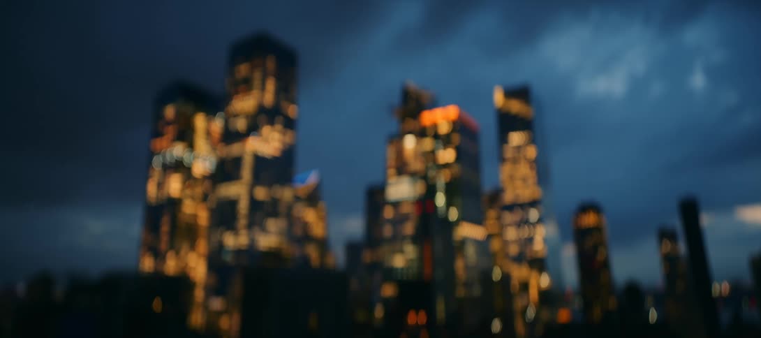 A blurry abstract view of a city skyline at night with the illuminated windows of the skyscrapers creating a beautiful bokeh effect