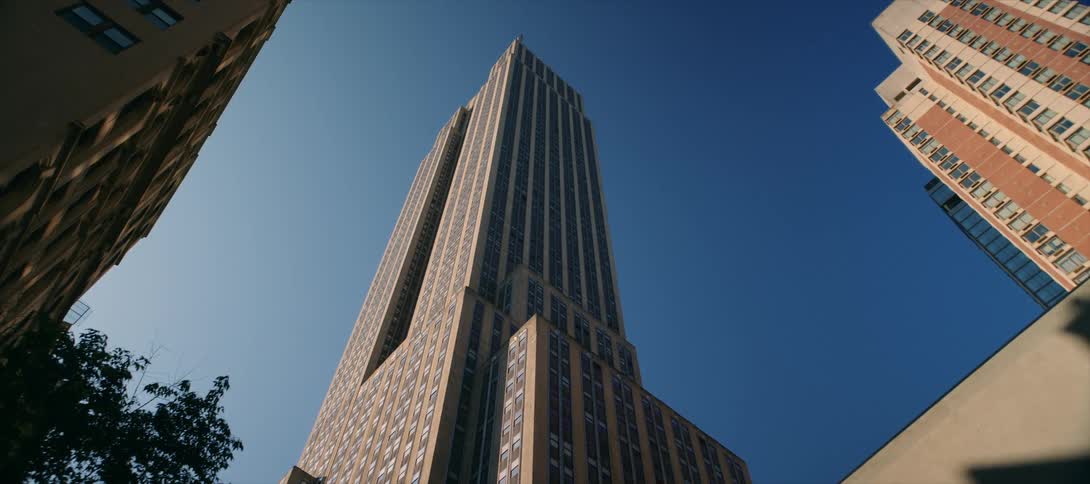 A static lowangle shot looks up at the full height of the iconic empire state building set against a cloudless deep blue sky in new york city