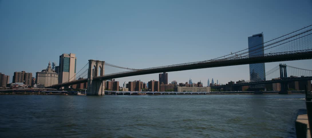 The brooklyn bridge spans the hudson river while vehicle traffic can be seen nearby
