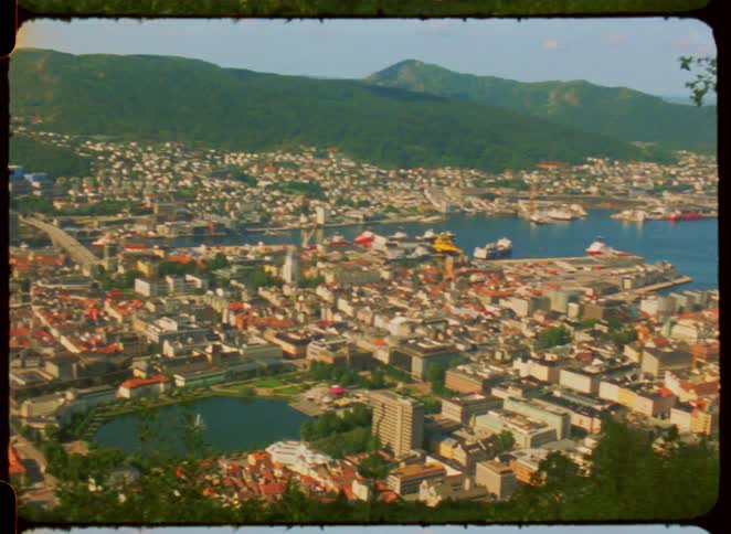 Panoramic view of a coastal city with a port and ships surrounded by mountains