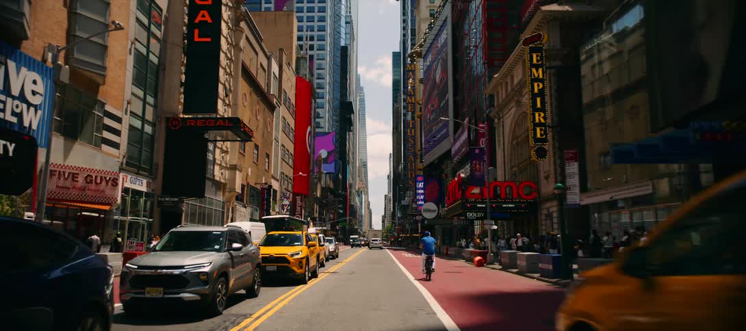A busy city avenue stretches between skyscrapers traffic streaming past and pedestrians walking