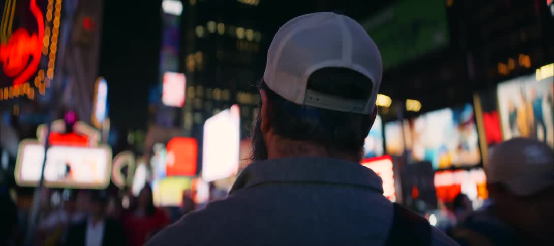 Close up of a young hispanic man standing outdoors on busy metropolitan street at night